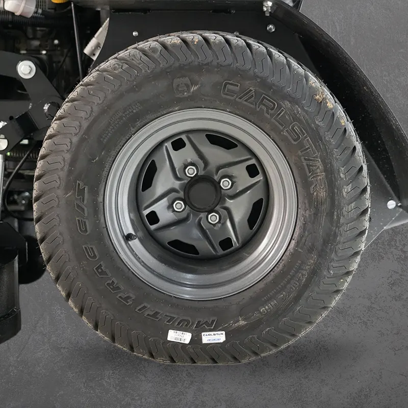 A close-up of a rugged black tire mounted on a dark steel wheel, shown against the underside of a vehicle.